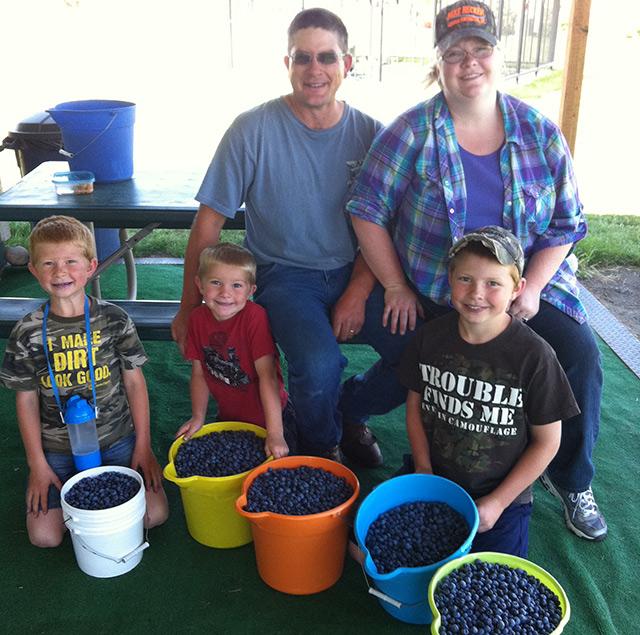5 people with 5 full buckets of blueberries