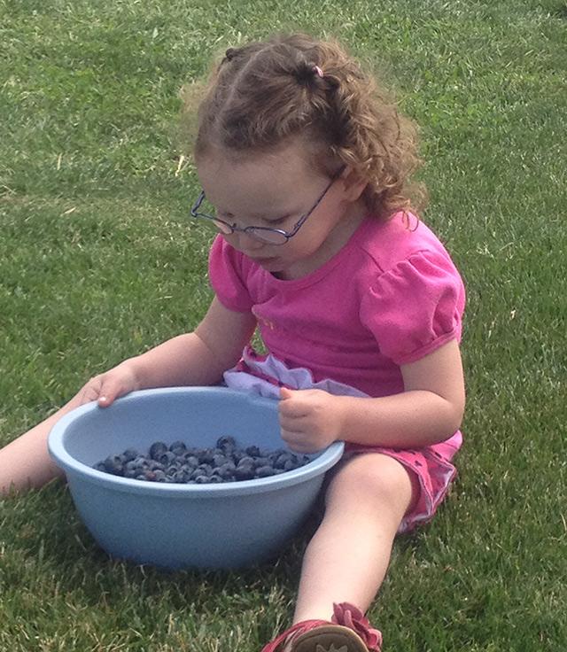 a young girl with a bowl of blueberries
