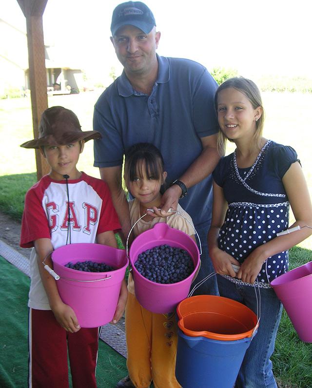 4 people with buckets of blueberries