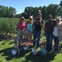 a group of people stand in front of a row of blueberries