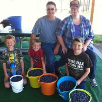 5 people with 5 full buckets of blueberries
